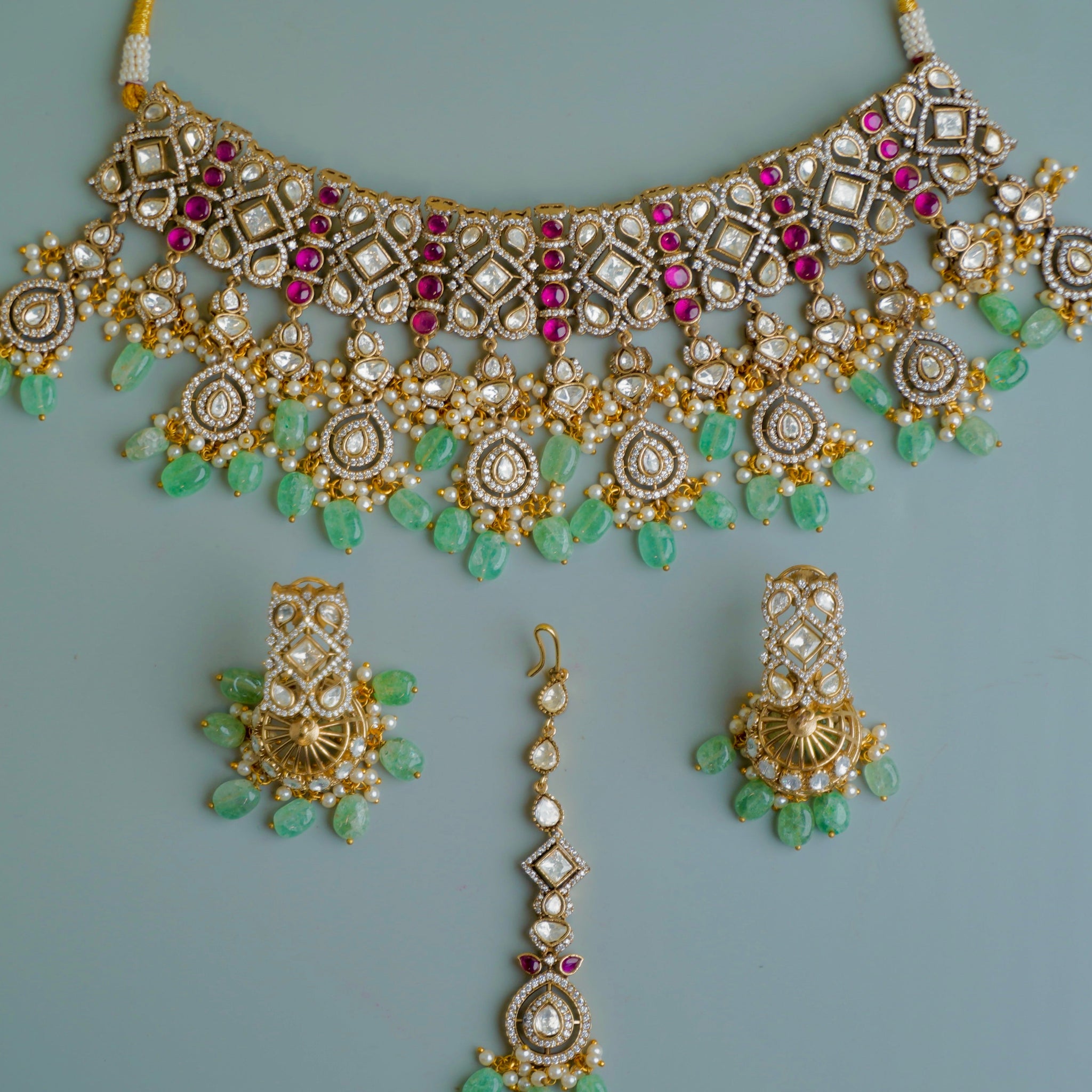 Ornate necklace with matching earrings on a light blue background