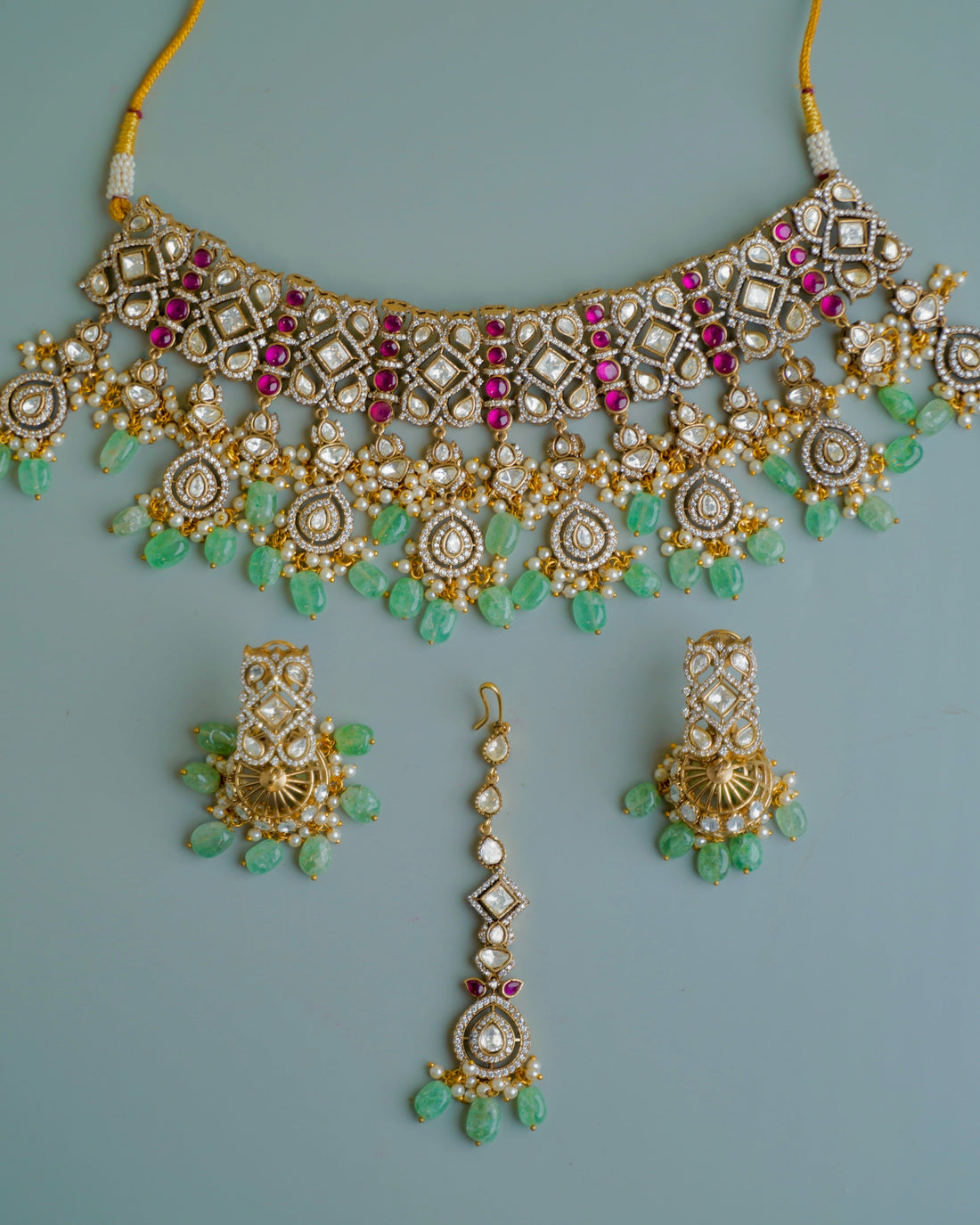 Ornate necklace with matching earrings on a light blue background